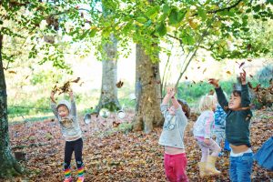 Children throwing leaves in air